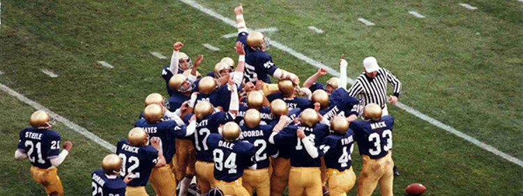The University of Notre Dame Football team carrying Daniel “Rudy” Ruettiger off the field in 1975.